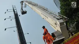 Petugas pemadam kebakaran (damkar) Jakarta Selatan menggunakan unit aerial fire fighting and rescue hydraulic platform atau mobil tangga berusaha menurunkan Agustinus Woro alias Martinus, Jakarta, Jumat (26/5). (Liputan6.com/Helmi Afandi)