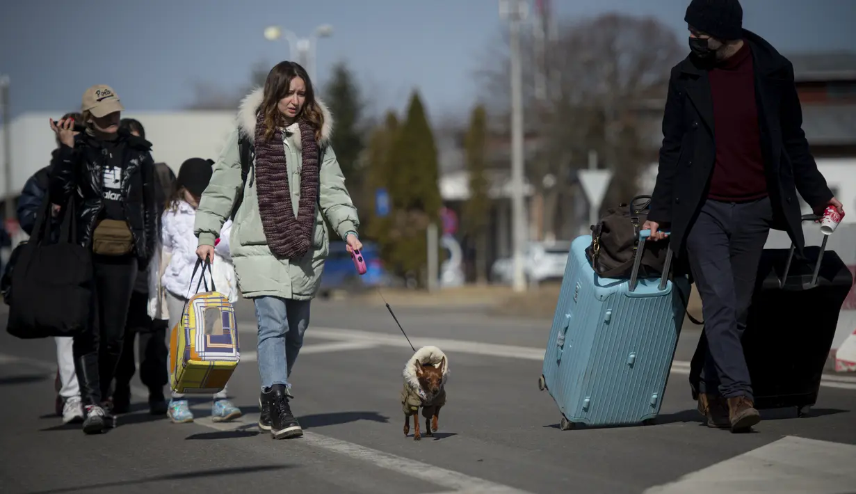 Seorang wanita berjalan dengan anjingnya setelah melintasi perbatasan dari Ukraina di perbatasan Rumania-Ukraina, di Siret, Rumania (25/2/2022). Ribuan orang Ukraina melarikan diri dari perang dengan melintasi perbatasan mereka ke barat untuk mencari keselamatan. (AP Photo/Alexandru Dobre)