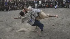 Pria Afghanistan bergulat di latar belakang selama tontonan gulat mingguan yang diadakan di arena darurat di taman Chaman-e-Hozori, di Kota Kabul (12/11/2021). (AFP/Hector Retamal)
