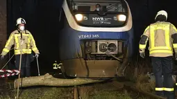 Petugas pemadam kebakaran membersihkan pohon dari rel kereta api setelah badai di Dorsten, Jerman, Kamis (17/2/2022). Deutsche Bahn telah menangguhkan layanan jarak jauh di beberapa wilayah Jerman karena badai. (Bludau Foto/dpa via AP)