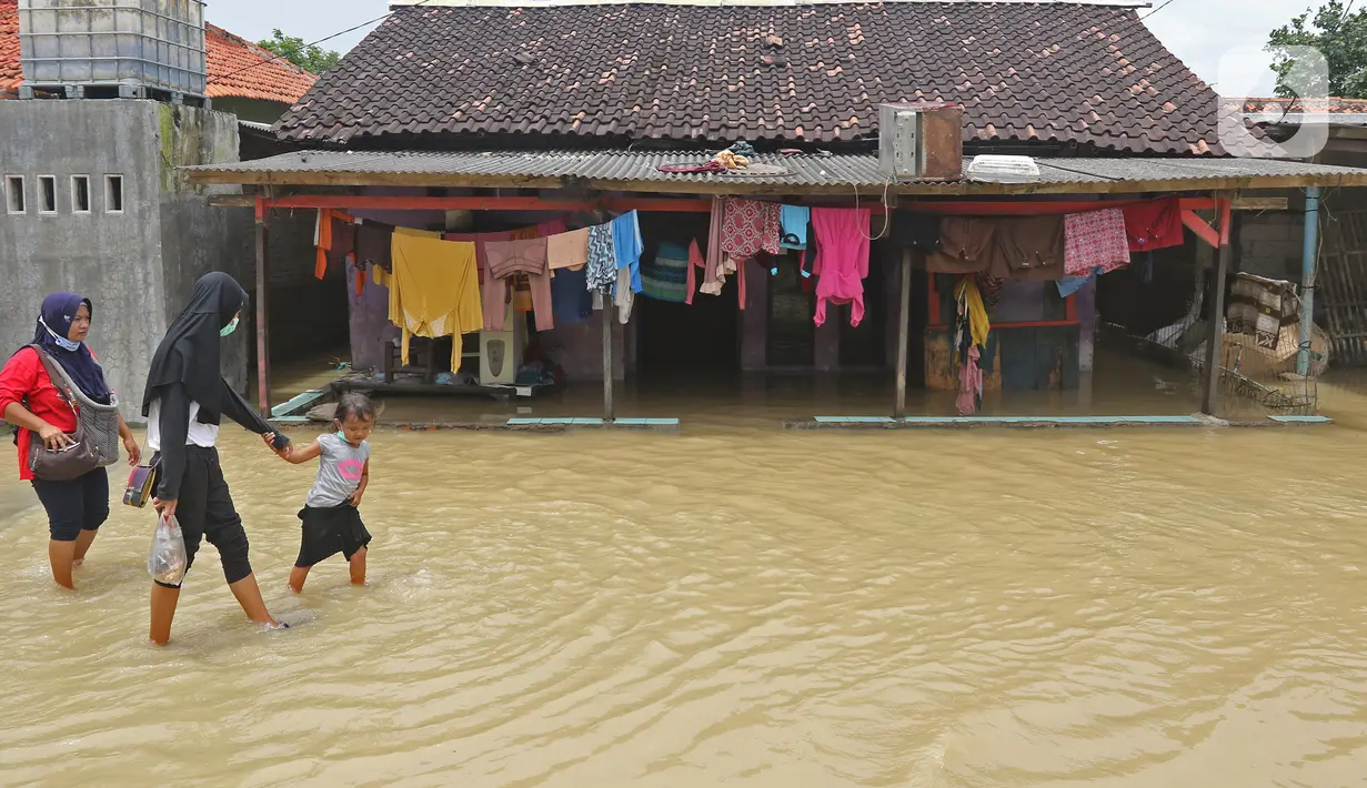 Warga berjalan melintasi rumah yang terendam banjir di Desa Karangligar, Kecamatan Telukjambe Barat, Karawang, Jawa Barat, Kamis (10/2/2021). Banjir akibat meluapnya sungai Citarum dan Cibeet tersebut membuat ratusan rumah terendam banjir dan ratusan hektar sawah. (Liputan6.com/Herman Zakharia)