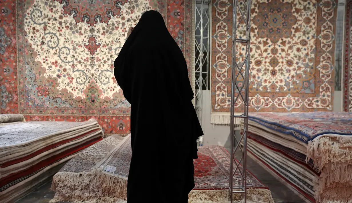 Pengunjung melihat-lihat karpet tenun yang dipamerkan dalam pameran di Teheran, Iran, Kamis (29/8/2019). AS menghentikan impor karpet Iran setelah Presiden Donald Trump menjatuhkan sanksi terkait program nuklir negara tersebut. (AP Photo/Vahid Salemi)