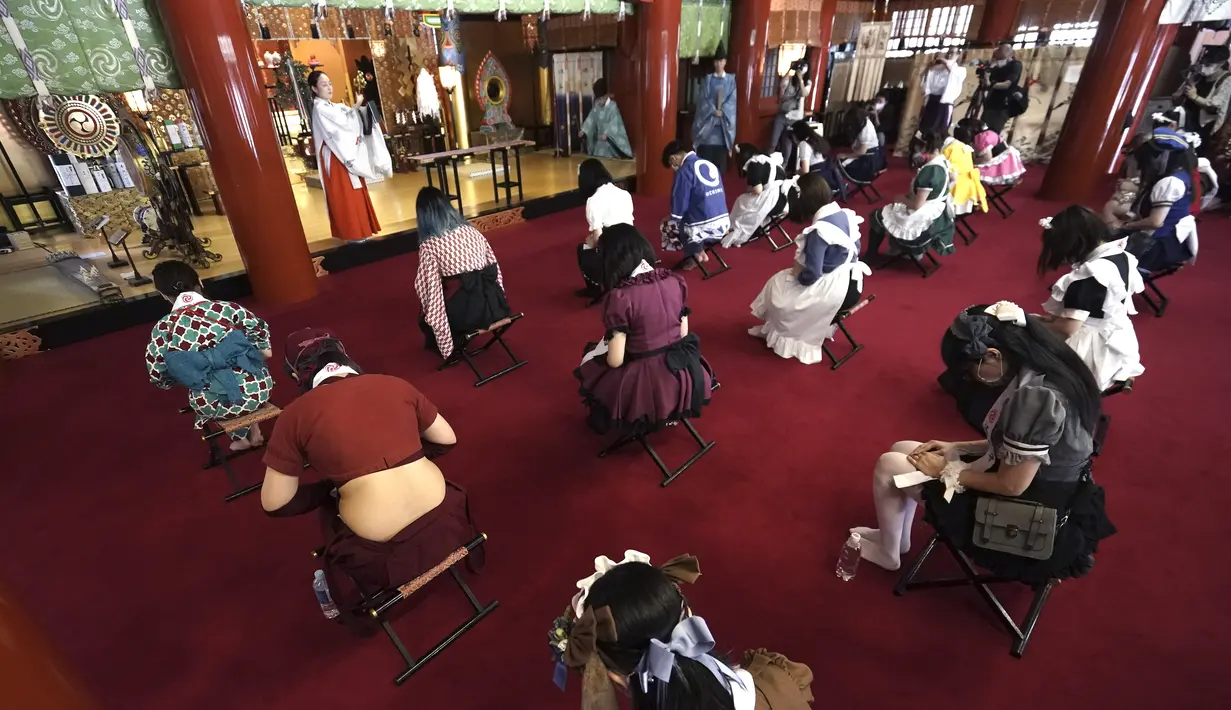 Para karyawan yang mengenakan kostum pelayan dari beberapa kafe bertema pembantu di Akihabara berdoa selama pertemuan doa untuk perlindungan dari COVID-19 dan untuk bisnis yang berkembang pesat di kuil Kanda Myojin, Tokyo (25/7/2020). (AP Photo/Eugene Hoshiko)