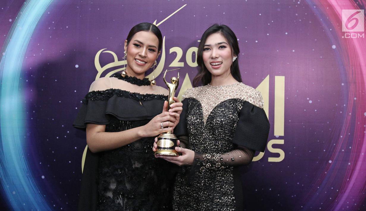 Penyanyi Raisa dan Isyana Sarasvati memenggang piala usai meraih penghargaan dalam Anugerah Musik Indonesia (AMI) Awards 2017 di Teater Garuda TMII, Jakarta, Kamis (16/11). (Liputan6.com/Herman Zakharia)