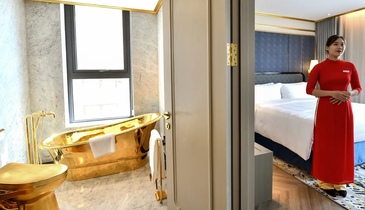 Seorang pegawai berpose di dalam kamar suite eksekutif seharga USD 1.000 per malam di hotel Dolce Hanoi Golden Lake yang baru saja diresmikan di Hanoi, Vietnam pada Kamis (2/7/2020). Hotel tersebut merupakan hotel berlapiskan emas 24 karat pertama di dunia. (Manan VATSYAYANA / AFP)