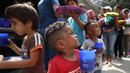Anak-anak pengungsi Venezuela mengantre makanan di tempat penampungan Divina Providencia, La Parada, Cucuta, Kolombia, Senin (18/2). Makanan terdiri dari kacang-kacangan, daging bologna, nasi, dan sepotong pisang. (AP Photo/Fernando Vergara)