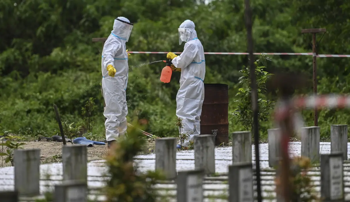 Relawan yang mengenakan pakaian alat pelindung diri (APD) melakukan pembersihan setelah penguburan seseorang yang diduga meninggal akibat virus Corona Covid-19 di sebuah pemakaman, di Yangon (26/10/2020). (AFP/Ye Aung Thu)