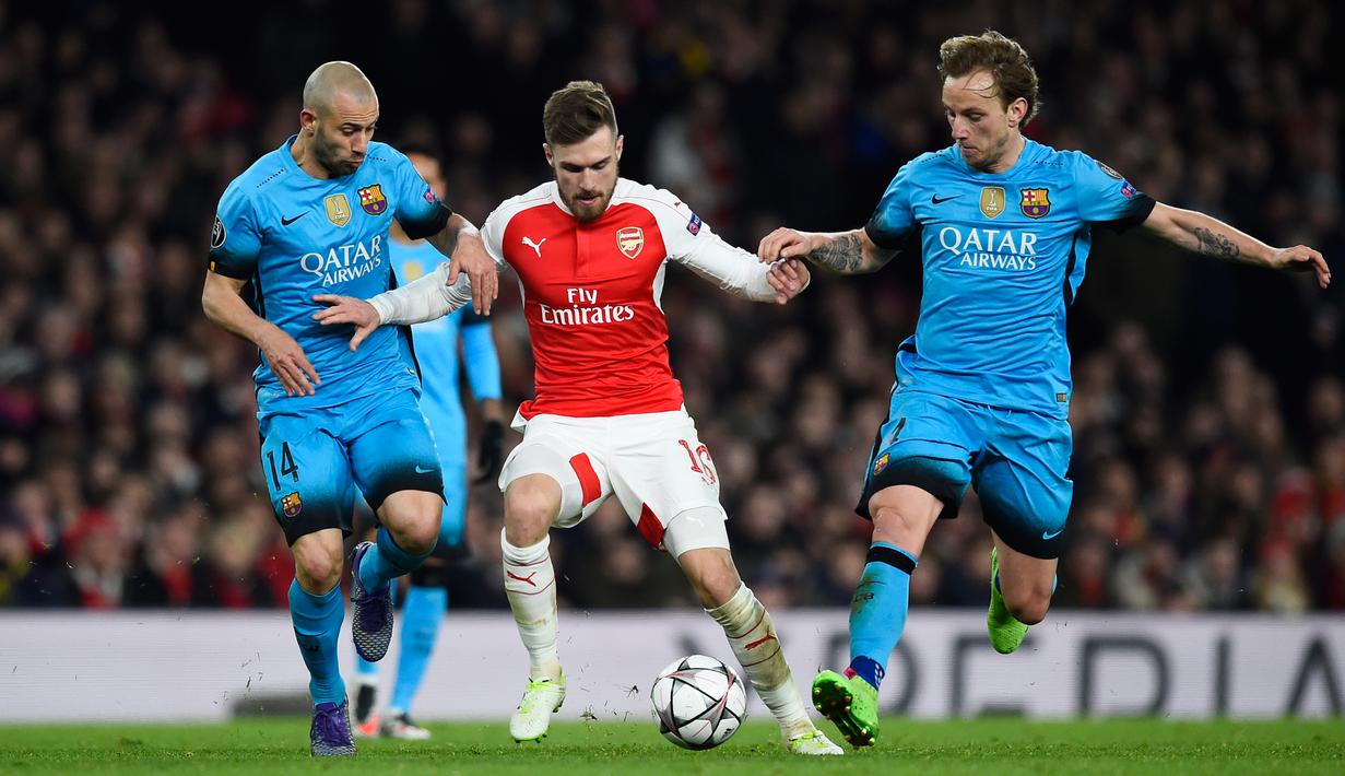 Aaron Ramsey berusaha melewati dua gelandang tangguh Barcelona, Javier Mascherano dan ivan rakitic pada leg pertama 16 besar Liga Champions di Stadion Emirates, Inggris (24/2). Barcelona menang atas Arsenal dengan skor 2-0. (Reuters/Dylan Martinez)