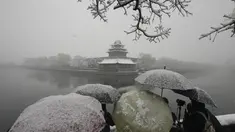 Pengunjung berkerumun untuk mengambil foto di tempat yang indah untuk Kota Terlarang saat salju turun di Beijing, China (18/3/2022). Gelombang dingin melanda banyak bagian China, menyebabkan suhu turun dan mengganggu lalu lintas di daerah yang terkena dampak. (AP Photo/Ng Han Guan)