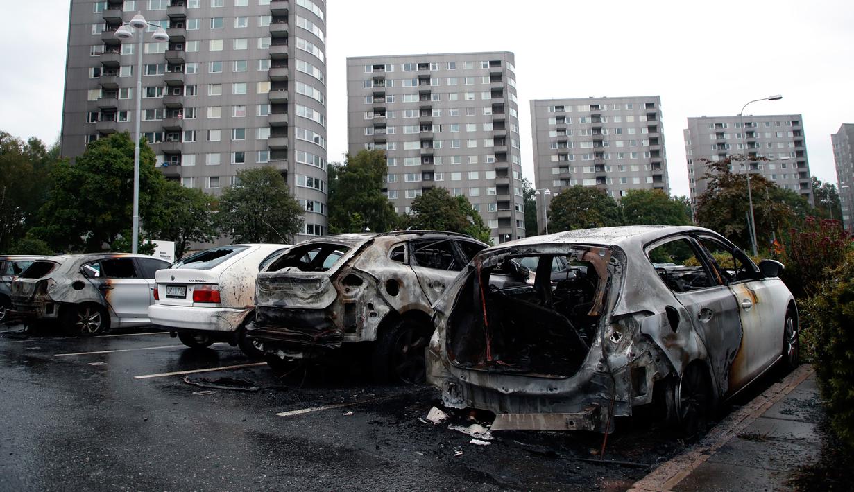 Deretan mobil yang terparkir di kota Gothenburg, Swedia hangus dan rusak, Selasa (14/8). Sekelompok orang bertopeng dan berpakaian hitam dilaporkan menjadi pelaku pembakaran puluhan mobil di sejumlah kota dalam semalam. (Adam Ihse/TT via AP)