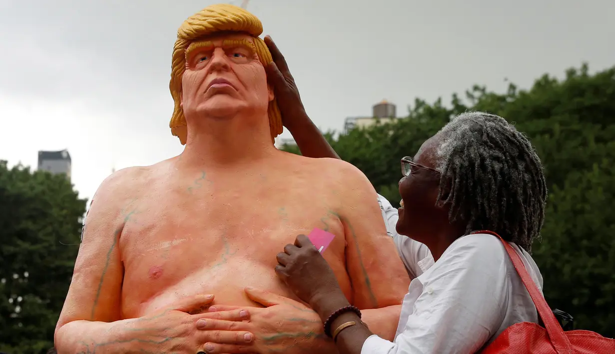Seorang nenek memegang kepala patung Donald Trump tanpa busana yang dipajang di Union Square Park, AS, Kamis (18/8). Warga di sekitar Union Square Park, New York, rela mengantre untuk berfoto dengan patung tersebut. (REUTERS/Brendan McDermid)