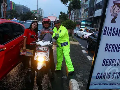 Seorang petugas bersama Pandu Jalan Fullo melakukan sosialisasi tertib berlalu lintas di kawasan perempatan Cideng, Jakarta, Senin (23/2). (Liputan6.com/Johan Tallo)