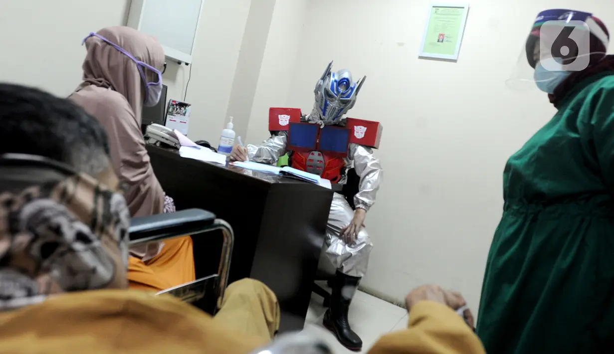 Dokter Rollando Erric Manibuy SpOT mengenakan alat pelindung diri (APD) ala transformer saat melayani pasiennya di RS Vania, Bogor, Jawa Barat, Jumat (22/5/2020). Penggunaan APD unik sejak merebaknya COVID-19 tersebut agar pasien tetap optimis meski sedang dalam pandemi. (merdeka.com/Arie Basuki)