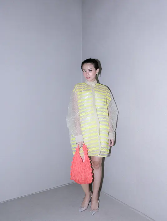 Ayu Shita tampil penuh warna dengan dress bernuansa kekuningan. Ia padukan penampilannya dengan kitten heels silver yang tak kalah manis dan tas merah. [Foto: Document/FIMELA]