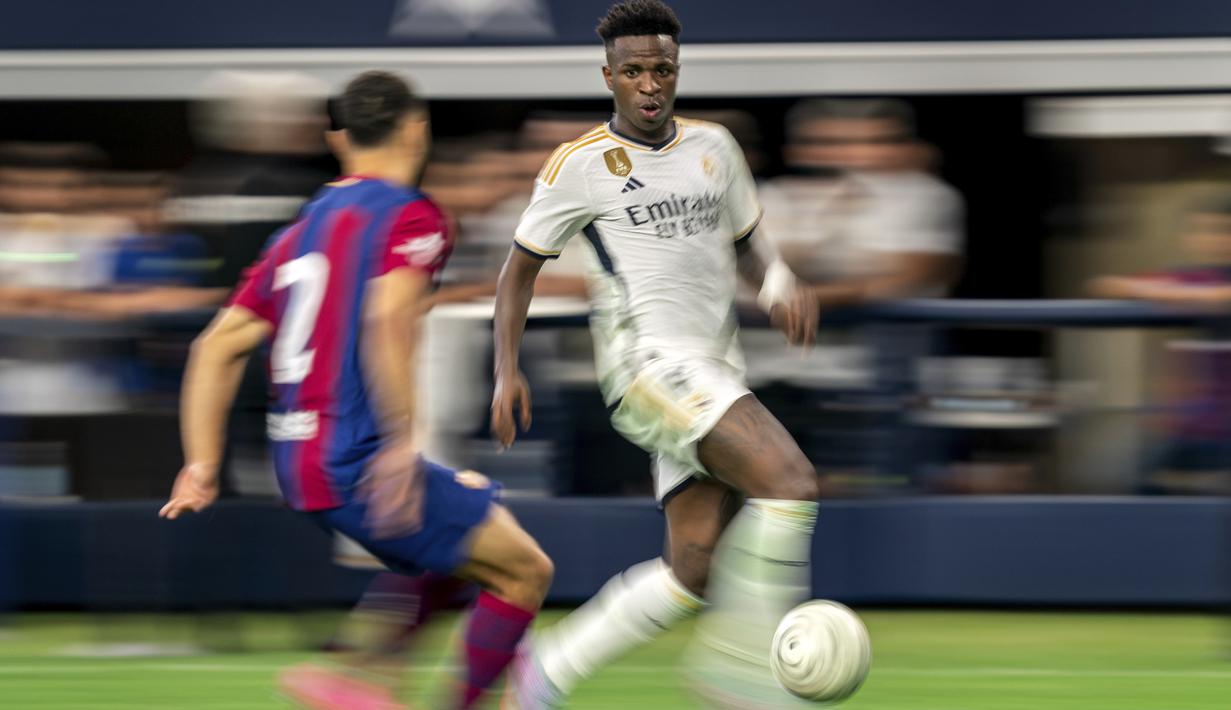 Pemain depan Real Madrid Vinicius Jose Paixao (kanan) mencoba menggiring bola melewati bek FC Barcelona Sergino Dest dalam laga pramusim bertajuk Soccer Champions Tour di AT&T Stadium, Texas, Amerika Serikat, Minggu (30/7/2023) dini hari WIB. (AP Photo/Jeffrey McWhorter)