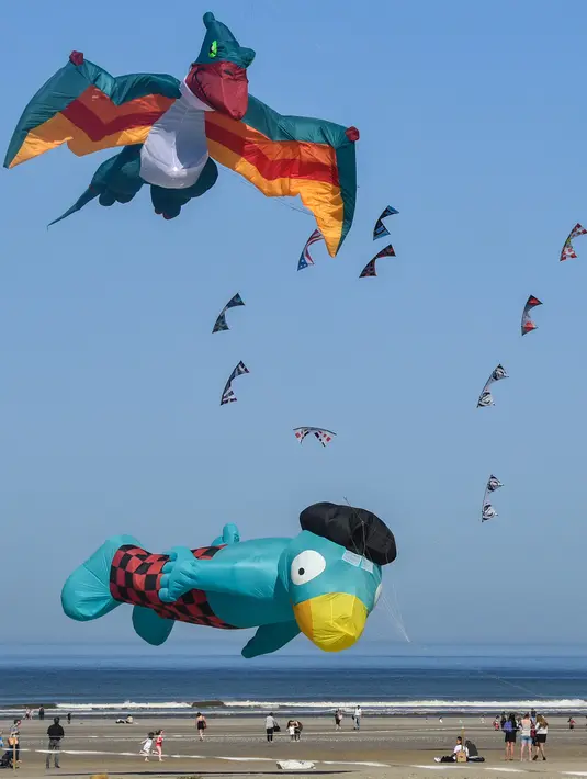 Orang-orang menerbangkan layang-layang berbagai bentuk dan warna dalam Festival Layang-Layang Internasional ke-32 di pantai Berck-sur-Mer, Prancis utara, 18 April 2018. Kegiatan internasional ini berlangsung hingga 22 April 2018. (Denis Charlet/AFP)