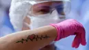 Seorang pekerja medis menunjukkan tatonya saat merayakan tiga pasien yang terakhir meninggalkan rumah sakit lapangan di Stadion Nasional Mane Garrincha di Brasilia, Brasil, Kamis (15/10/2020). Mereka berkumpul saat pasien COVID-19 terakhir pulang setelah dinyatakan sembuh. (AP Photo/Eraldo Peres)