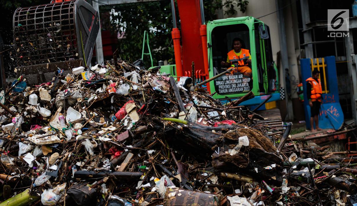 Petugas mengeruk sampah menggunakan alat berat di pintu air Manggarai, Jakarta, Selasa (4/12). Tingginya intensitas hujan di wilayah Jabodetabek membuat sampah yang terbawa arus sungai menumpuk di Pintu Air Manggarai. (Liputan6.com/Faizal Fanani)