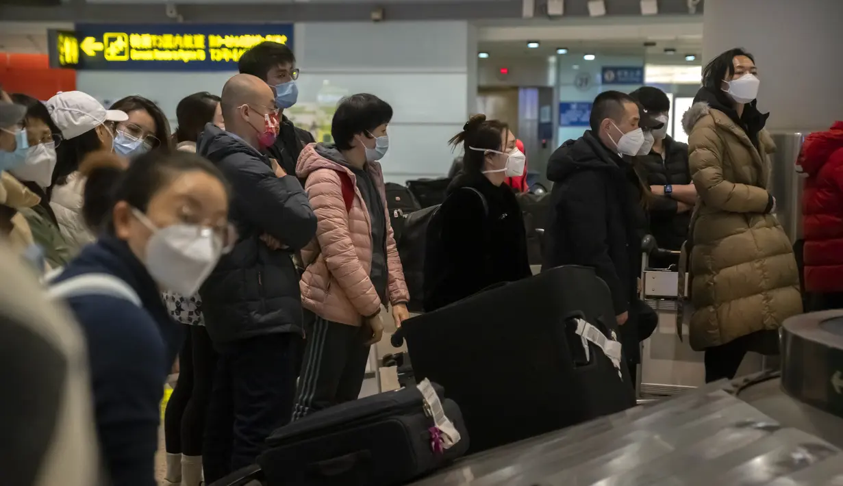 Pelancong yang memakai masker menunggu barang bawaan mereka di area kedatangan internasional di Bandara Internasional Ibukota Beijing di Beijing, Senin (9/1/2023). Pelancong internasional pertama tiba di China tanpa karantina wajib yang telah diberlakukan pada awal penerbangan. Pandemi tiga tahun lalu setelah pembatasan dicabut mulai hari Minggu. (AP/Mark Schiefelbein)