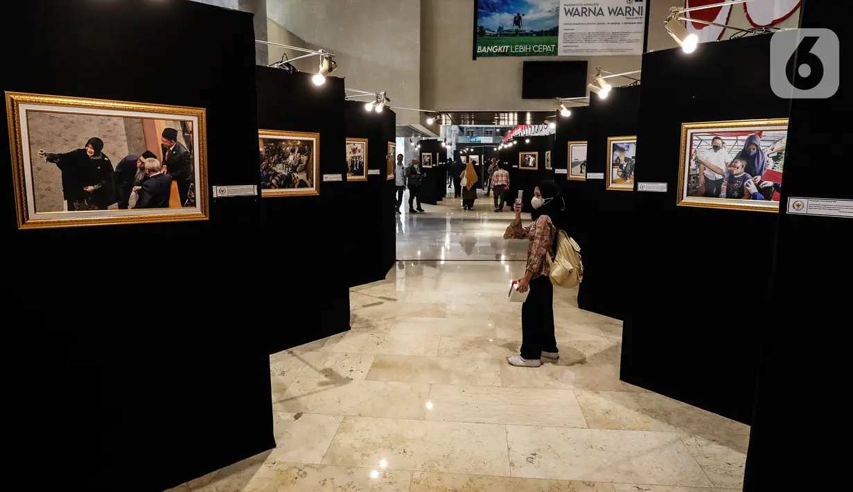 Pengunjung melihat karya foto dalam Pameran Foto Jurnalistik Warna-Warni Parlemen dengan tema Bangkit Lebih Cepat di loby Nusantara II DPR, Senayan, Jakarta, Senin (29/8/2022). (Liputan6.com/Johan Tallo)