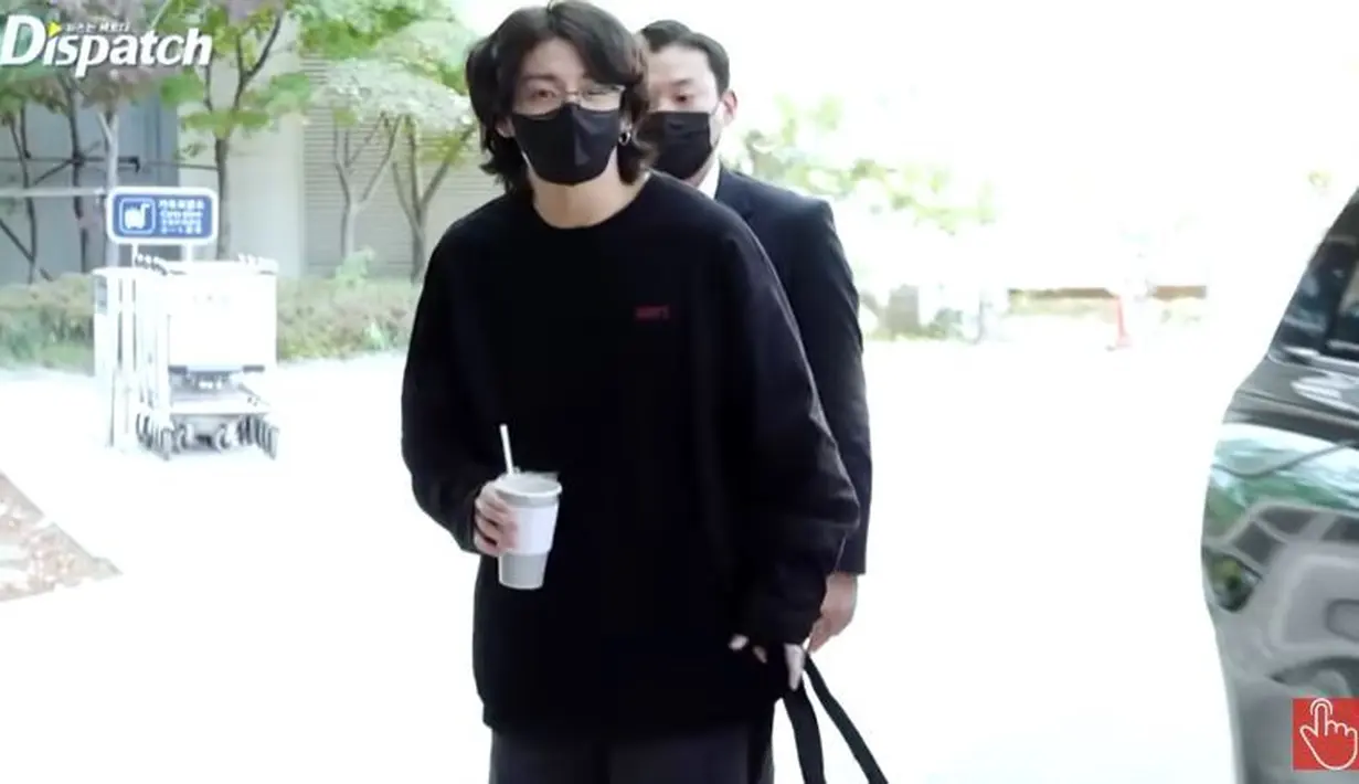 Saat keluar dari mobil, Jungkook menenteng sebuah tas yang tak terlalu besar. Pada salah satu tangannya, ia juga memegang gelas minuman. (Foto: Dispatch/Allkpop)