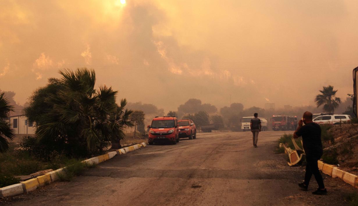 Warga dan petugas pemadam kebakaran berusaha memadamkan api saat asap dan kobaran api membumbung tinggi dari sebuah kawasan hutan menyusul kebakaran hutan di distrik Seferihisar, Izmir, Turki, pada 30 Juni 2025. (Ahmet Ayberk Cimen/AFP)