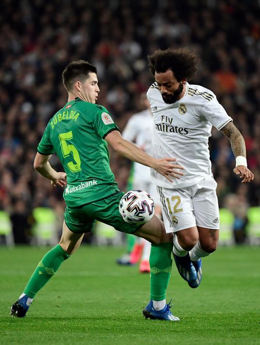 Gelandang Real Sociedad, Igor Zubeldia (kiri) berebut bola dengan bek Real Madrid, Marcelo pada laga perempat final Copa del Rey di Santiago Bernabeu, Kamis (6/2/2020). Real Madrid gagal melaju ke semifinal Copa del Rey setelah dibungkam Real Sociedad dengan skor 3-4. (JAVIER SORIANO/AFP)