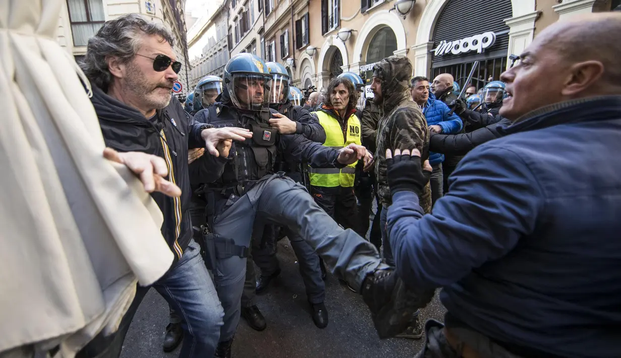 Petugas berusaha membubarkan sopir taksi yang menggelar demo di Roma, Italia, Selasa (21/2). Mereka mendesak pemerintah agar menutup layanan seperti Uber yang berbasis aplikasi. (AP Photo / Alessandra Tarantino)