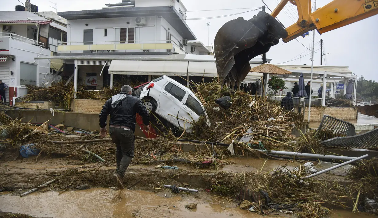Seorang pria melintasi jalan yang terendam banjir menyusul badai petir yang hebat, di desa Agia Pelagia, di pulau Kreta, Yunani, Sabtu (15/10/2022). Dilaporkan setidaknya satu orang tewas dan lainnya hilang setelah banjir bandang yang parah. (AP Photo/Harry Nakos)