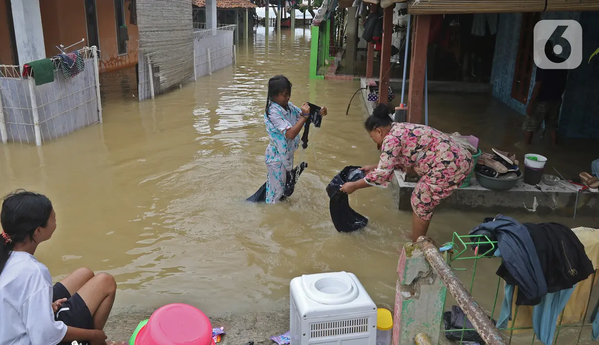 Seorang ibu mencuci pakaian dengan air banjir di Desa Karangligar, Kecamatan Telukjambe Barat, Karawang, Jawa Barat, Kamis (10/2/2021). Banjir di Desa Karangligar akibat meluapnya sungai Citarum dan Cibeet membuat ratusan rumah terendam banjir dan ratusan hektar sawah. (Liputan6.com/Herman Zakharia)