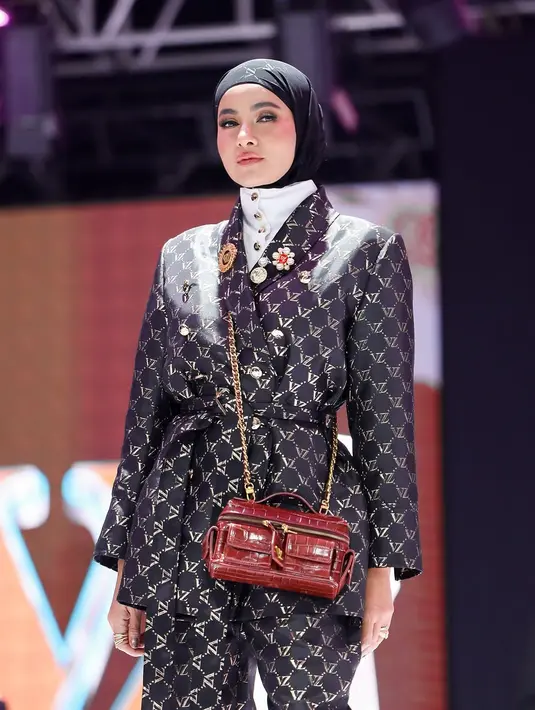 Ia mengenakan setelan blazer dan celana panjang bernuansa hitam dengan motif monogram khas Vivi Zubedi yang memberikan kesan mewah dan modern. [@vivizubedi].