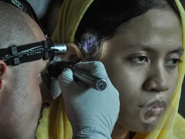 Relawan Starkey Hearing Foundation memakaikan alat bantu dengar pada seorang penyandang tunarungu di Gedung Kemensos, Jakarta, Jumat (27/3/2015). Alat ini diberikan gratis Kemensos bekerjasama dengan Starkey Hearing Foundation (Liputan6.com/Faizal Fanani)