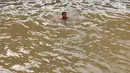 Anak-anak berenang di Sungai Kalimalang, Jakarta Timur, Jumat (5/7/2019). Tingginya suhu udara Ibu Kota akibat musim kemarau menyebabkan anak-anak tersebut berenang di Sungai Kalimalang meski dengan kondisi seadanya. (Liputan6.com/Immanuel Antonius)