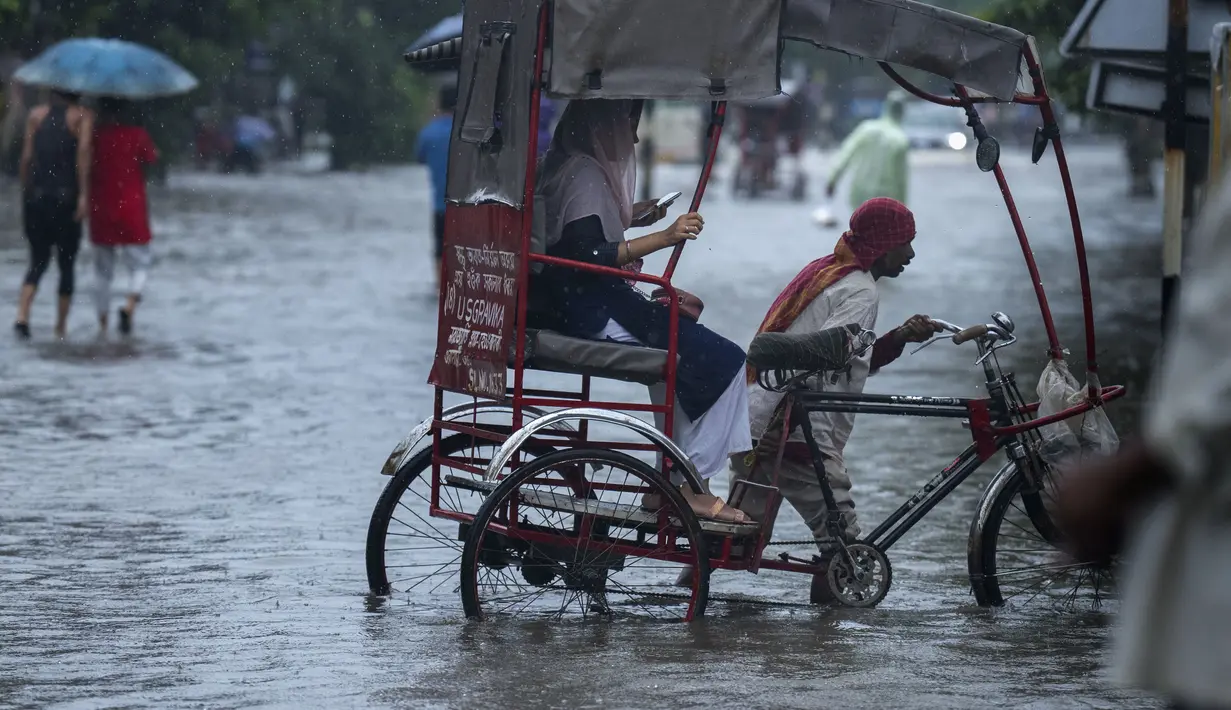 Seorang penarik becak membawa penumpang melewati genangan air saat hujan turun di Guwahati, negara bagian Assam, India, Kamis (16/6/2022). Guwahati telah menerima curah hujan 81,5 mm dalam 24 jam terakhir yang termasuk dalam kategori 'hujan lebat' dalam 24 jam terakhir. (AP Photo/Anupam Nath)