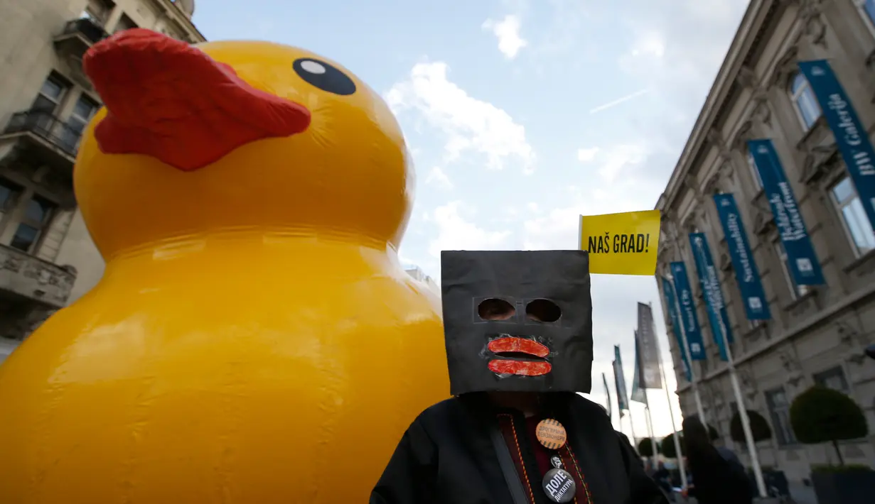 Bebek karet dibawa saat aksi mengkritik rencana tepi laut Belgrade di Beograd, Serbia, Selasa (25/4). Demo dilakukan satu tahun setelah pembongkaran misterius di daerah yang ditandai untuk proyek real estat yang didanai UEA. (AP Photo / Darko Vojinovic)