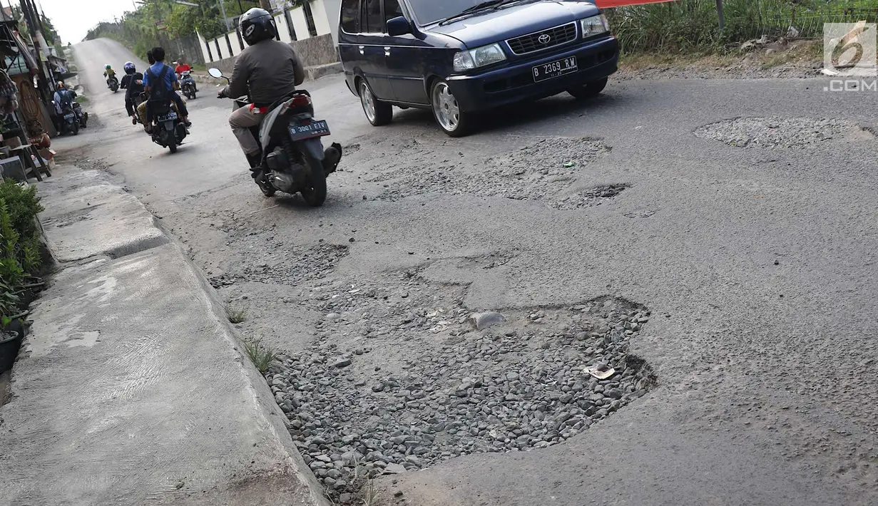 Pengendara melintasi jalan berlubang di kawasan Gas Alam, Depok, Jawa Barat, Kamis (4/10). Kondisi jalan rusak di kawasan tersebut mengganggu aktivitas warga. (Liputan6.com/Immanuel Antonius)