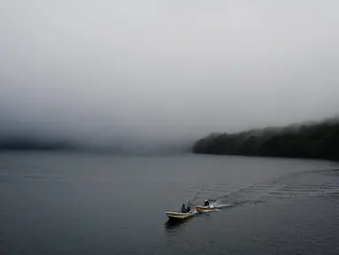 Dua pria mengendarai perahu di atas Danau Ashi di perfektur Kanagawa, Jepang (11/9/2019). Danau Ashi adalah sebuah sebuah danau cantik yang terletak pada wilayah Taman Nasional Hakone di Prefektur Kanagawa, Jepang. (AFP Photo/Charly Triballeau)