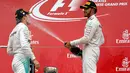 Lewis Hamilton sedang menyemprotkan sampanye ke arah Nico Rosberg dalam perayaan kemenangan seri ke-17 Formula One (F1) GP Jepang, Minggu (9/10). Kemenangan ini membuat Hamilton semakin tertinggal dari Rosberg. (REUTERS/Toru Hanai)