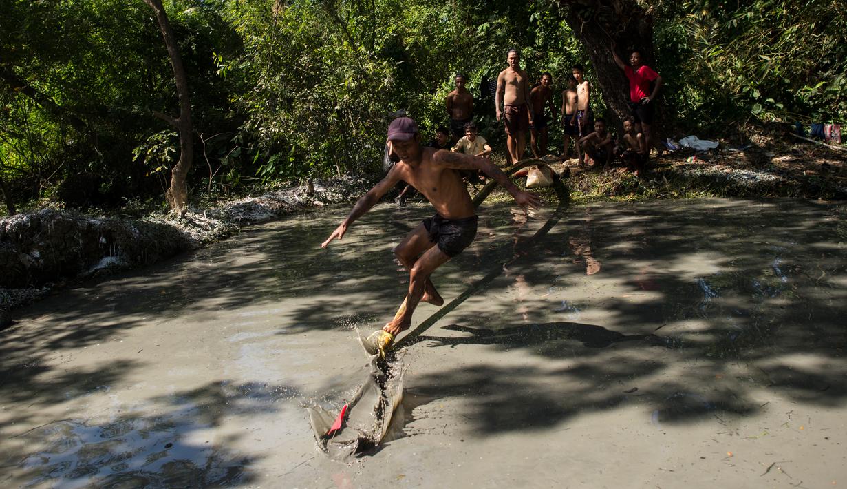 Seorang pria berjalan di atas tiang untuk mencoba meraih bendera nasional memperingati Hari Kemerdekaan Myanmar di pinggiran Yangon (4/1). Myanmar merayakan peringatan ke-71 deklarasi kemerdekaannya dari kolonial Inggris. (AFP Photo/Ye Aung Thu)