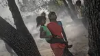 Seorang wanita menggendong putrinya saat terjadi kebakaran di daerah kumuh di Noida, pinggiran New Delhi, India, Minggu (11/4/2021). Dua anak tewas dan lebih dari 150 gubuk kumuh yang sebagian besar dihuni oleh para pemulung dalam kebakaran pada Minggu sore. (AP Photo/Altaf Qadri)