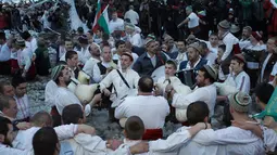 Sejumlah pria Bulgaria memainkan alat musik tradisional sambil menari di perairan sungai Tundzha selama Hari Epiphany di kota Kalofer, Bulgaria (6/1). Kegiatan ini juga dapat membawa kesehatan yang baik sepanjang tahun baru. (AP Photo/Valentina Petrova)