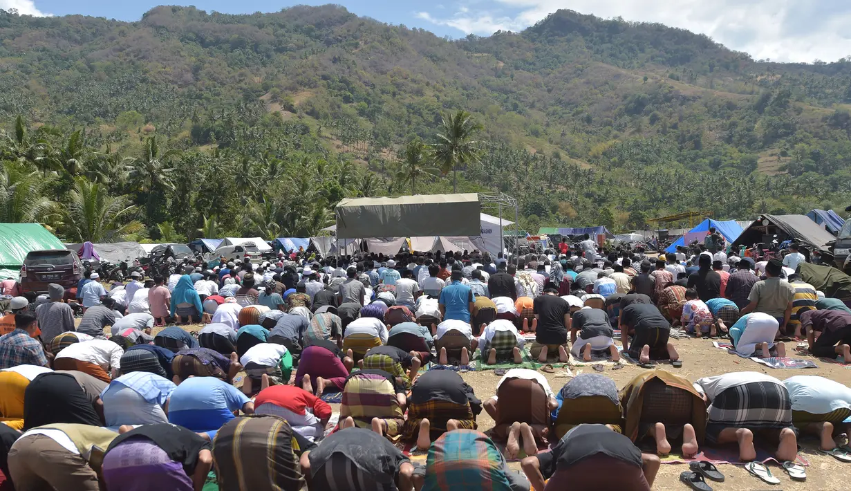 Umat muslim salat Jumat di sebuah ladang di dekat tempat penampungan sementara setelah gempa di Pemenang, Lombok (10/8). Menurut menteri senior, korban tewas akibat gempa dahsyat 6,9 SR di pulau Lombok melonjak di atas 300 orang. (AFP Photo/Adek Berry)