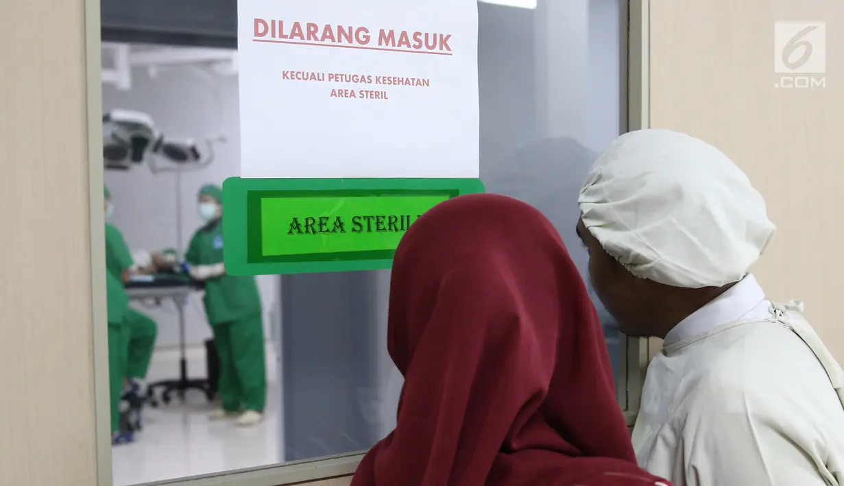 Orangtua pasien mengintip anaknya yang sedang operasi hernia di RS EMC, Bogor, Jawa Barat, Sabtu (21/4). Operasi hernia yang diberikan oleh RS EMC dikhususkan bagi warga kurang mampu. (Liputan6.com/Herman Zakharia)