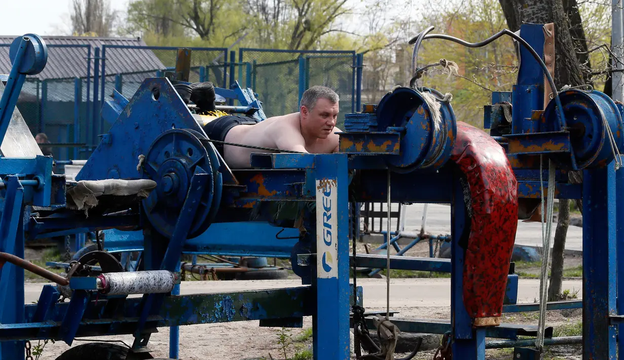 Seorang pria sedang berlatih di outdoor gym atau pusat kebugaran terbuka di tepi Sungai Dnipro, Kiev, Ukraina, Kamis (18/4). Ada lebih dari 200 alat fitness di pusat kebugaran yang berdiri sejak tahun 1970-an ini. (AP Photo/Efrem Lukatsky)