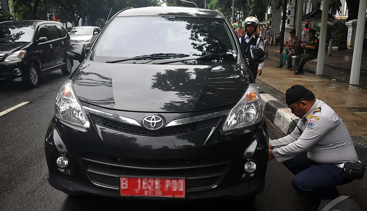 Petugas Dinas Perhubungan DKI Jakarta terlihat sedang mengempiskan mobil yang terparkir di depan Gedung DPRD, Jakarta, Senin (12/1/2015).  (Liputan6.com/Johan Tallo)