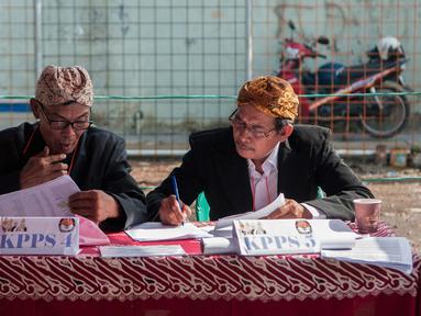Petugas KPPS mengenakan pakaian adat dan belangkon melihat lembaran data pemilih di TPS 14 Cipinang Besar Selatan, Jakarta, Rabu (19/4). Petugas KPPS menggunakan pakaian adat tersebut agar warga tertarik untuk mencoblos. (Liputan6.com/Gempur M. Surya)