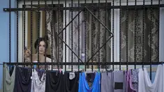 Seorang wanita menyaksikan pemutaran film bertema kekerasan aparat, dalam sebuah festival 'outdoor' di Bucharest, Rumania (31/8/2021). International Roma Theatre Festival digelar di permukiman warga ekonomi rendah. (AP Photo/ Vadim Ghirda)