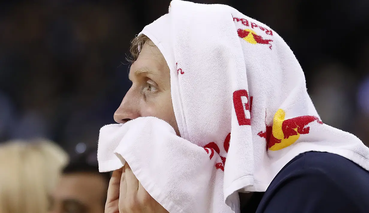 Pemain Dallas Mavericks, Dirk Nowitzki duduk terpaku dibangku pemain cadangan saat timnya kalah dari Warriors pada laga NBA basketball game  di Oakland, California, (30/12/2016). Warriors menang 108-99. (AP/Tony Avelar)