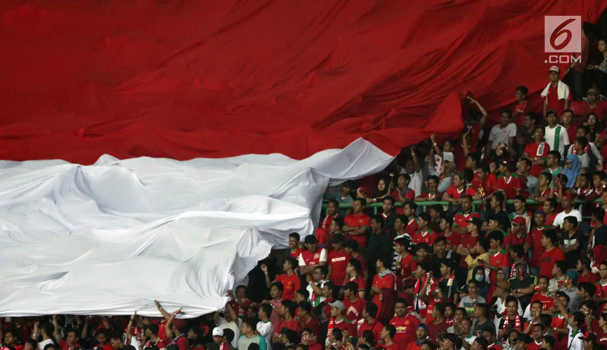 Suporter Timnas Indonesia membentangkan bendera raksasa saat menyaksikan laga persahabatan antara Indonesia melawan Fiji di Stadion Patriot Candrabhaga, Bekasi, Sabtu (9/2). Laga berakhir imbang 0-0. (Liputan6.com/Helmi Fithriansyah)