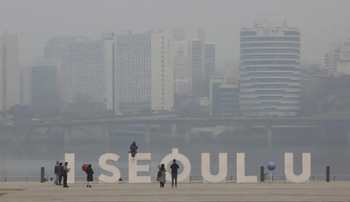 Seorang wanita mengenakan masker berpose saat pemandangan kota ditutupi dengan kabut tebal partikel debu halus di Seoul, Korea Selatan, Selasa (5/3). (AP Photo/Ahn Young-joon)